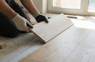 a man is laying down on the floor and cutting a piece of wood