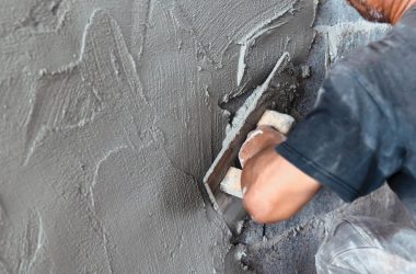 closeup hand of worker plastering cement at wall in construction